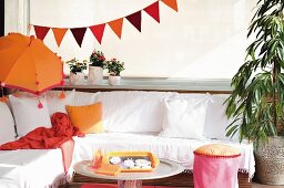 Comfortable corner bench with white cover, orange Balinese parasol and bunting