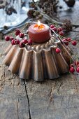 A baking tin with a candle and hawthorn berries