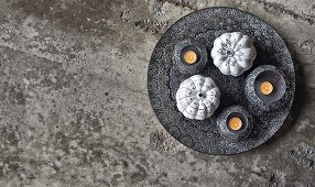 Ornamental squashes painted black and white and tealights in bowls