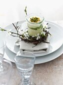 Mascarpone desert with kiwis and pistachio nuts decorated with twigs and flowers