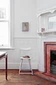 Antique metal chair next to fireplace with red tiled surround