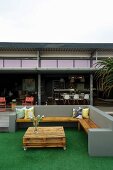 Coffee table made from pallets and castors and corner bench on terrace outside shipping-container house with long open side