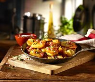 Fried potatoes with bacon and rosemary in a rustic pan