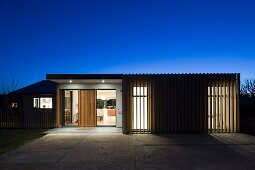 Twilight atmosphere; illuminated, contemporary house with view of interior through large windows