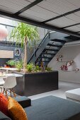 Green plants in open-plan living area next to steel staircase