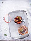 Damsons with rosemary in preserving jars (seen from above)