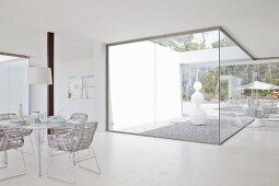 View from bright dining area to white sculpture in atrium with floor-to-ceiling glass walls