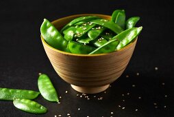Mange tout with sesame seeds in a wooden bowl (Paleo diet)