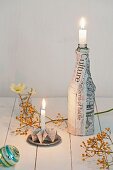 Weihnachtliche Tischdeko: Gefalteter Kerzenhalter und Flasche ummantelt mit Zeitungspapier