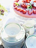 A strawberry tart and teacups on a garden table