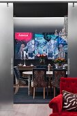 Gepolsterte Stühle im Leoparden-Look um Tisch, in grau getöntem Esszimmer mit modernem Bild an Wand