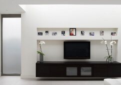 Schwarzes Lowboard und Flachfernseher in Wandnische in zeitgenössischem Wohnzimmer