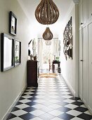 Gallery of pictures and low-hanging ceiling lamps in hallway with chequered floor