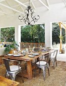 Large dining table and Industrial-style metal chairs on roofed terrace furnished in shades of brown