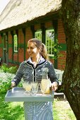 A woman serving elderflower spritzers in a garden