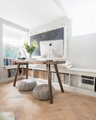 Knitted pouffes below rustic computer desk in front of fitted filing shelves also used as bench and shelf below framed chalkboard on wall