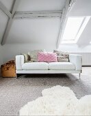 White two-seater sofa with scatter cushions and vintage wooden trunk in attic room