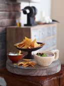 Tortilla chips with a bean dip and a sour cream dip on a wooden board