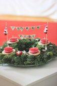 Advent wreath decorated with Father Christmas figurines and lettering on bunting with festive greeting in German