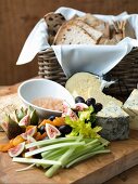 A cheese platter with vegetables, fruit and a bread basket