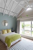 Modern attic bedroom with exposed roof structure painted white