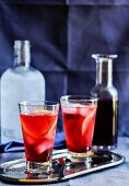 Two cocktails with hibiscus syrup, ice cubes and orange slices