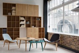 Classic easy chairs with covers in different colours and side tables in front of shelving unit with open compartments and cabinet doors in corner of loft apartment