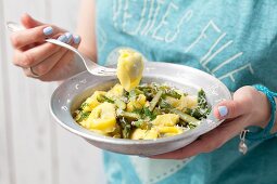 Frau isst Tortelloni mit Spargel, Zitronensauce und Parmesan