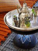 Moroccan teapot and tea glasses on silver tray on modern side table