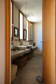 Blick in ein Badezimmer im Ethnostil mit verschiedenen Körben unter dem Waschtisch