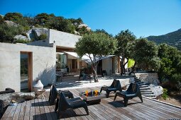 Terrasse eines mediterranen Bungalows mit Olivenbäumen und modernen Stühlen aus Kunststoff