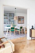 Blick von Wohnraum durch offene Schiebetür auf Essplatz, Retro Stühle mit grünen Polstern um weissen Tisch