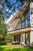 Zeitgenössisches Wohnhaus mit möblierter Terrasse, darüber Balkon