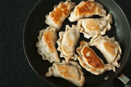 Fried pierogi (Polish meat dumplings) in a frying pan
