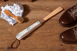 Shoe horn with hand-made handle and shoe brush on wooden floor