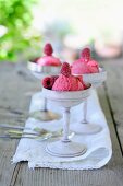 Three bowls of raspberry ice cream on a garden table