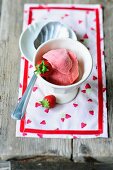A bowl of strawberry ice cream with fresh strawberries