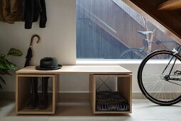 Fedora on simple, modern cloakroom cabinet and bicycle in hallway