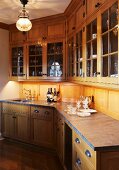 Elegant, rustic, country-house kitchen with glass-fronted wall cabinets, bottles of wine and silver jug