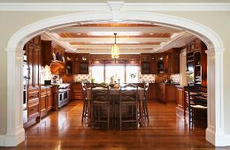 Elegant, spacious, country-house kitchen with wooden fronts, wall units and glossy, exotic-wood parquet flooring