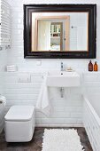 White subway tiles in small bathroom; mirror with black vintage frame