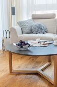 Knitted cushion and flower-shaped cushion on pale couch behind coffee table