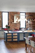 Row of lights above island counter with ample storage space and kitchen counter against brick wall