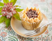 A cupcake with orange cream and chocolate chunks