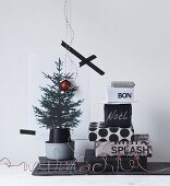 Stack of gifts wrapped in black and white paper next to printed picture of Christmas tree