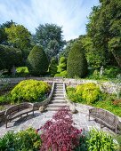 Elegante, sommerliche Parkanlage mit Sitzplätzen, im Hintergrund Treppe und Formgehölze