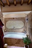 Rustic, modern bathroom with wood-beamed ceiling and fitted bathtub with stone-tiled surround