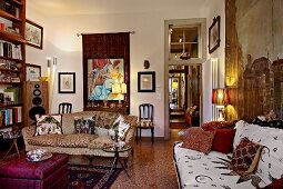 Living room with sofas and coffee table on terrazzo floor, various lamps and wall hangings