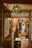 Wreath hung on wooden beam above door and view into rustic interior with exposed brick wall