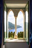 Façade element with pointed arches and Corinthian column behind open window with view of coastal landscape (Villa Cimbrone Hotel)